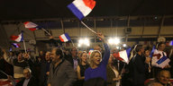 Frauen und Männer schwenken Frankreich-Flaggen.