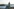 Der Pegelturm an den St.-Pauli-Landungsbrücken mit Blick auf den Hafen und zahlreiche Hafenkräne im Hintergrund.