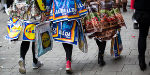 Karnavalistinnen in Köstümen aus Discounter-Plastiktüten laufen durch Köln
