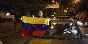 Ein Mann hält eine venezolanische Fahne aus einem Auto
