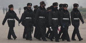 Sicherheitsleute laufen durch den Smog am Platz des Himmlischen Friedens.