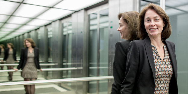 Eine Frau steht lächelndt in einem verspiegeltem Aufzug