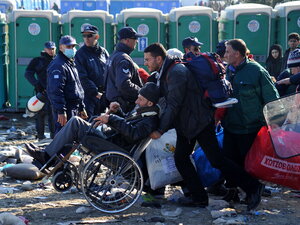 Menschen mit einem Rollstuhlfahrer vor einer Reihe Dixi-Klos Menschen mit einem Rollstuhlfahrer vor einer Reihe Dixi-Klos