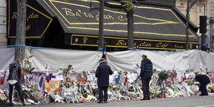 Menschen legen Blumen vor dem Bataclan Café ab