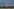 Blitz an dunklem Himmel über Wald und Feldern