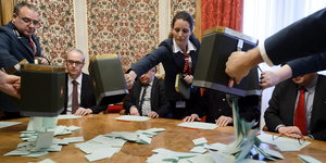 Wahlhelfer schütten Urnen mit Wahlzetteln auf den Tisch.