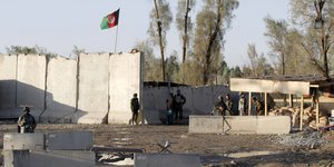 Afghanische Soldanten stehen zwischen Betonmauern, darüber die afghanische Fahne