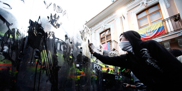 Protestierende haben die Schutzschilder der Riotpolice mit Öl verschmiert, einer zeigt ihnen den Mittelfinger