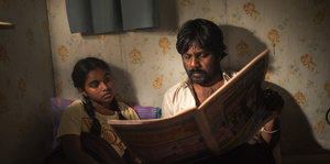 Ein Mann und ein Junge schauen gemeinsam in eine Zeitung