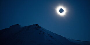 Sonnenfinsternis über einem verschneiten Berg