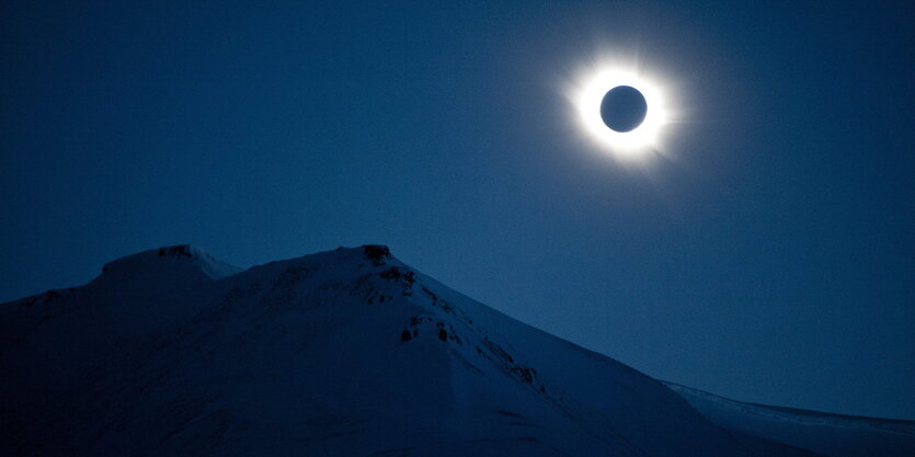 Sonnenfinsternis über einem verschneiten Berg