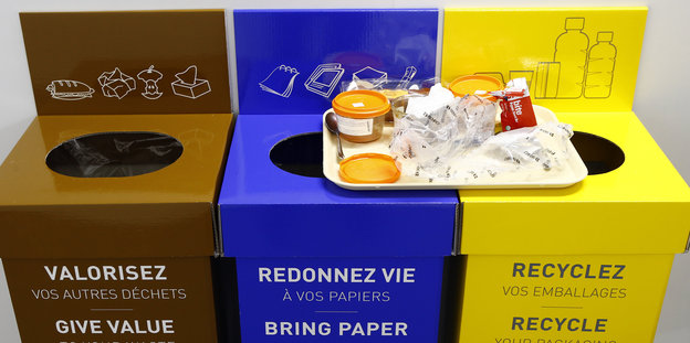 Ein Tablett mit Essensverpackungen steht auf Mülleimern