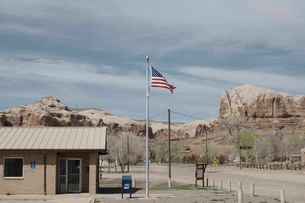 Gleißendes Licht, Berge, im Vordergrund ein Holzhaus davor ein Fahnenmast wehender amerikanischen Flagge