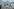Ein Stacheldrahtzaun im Vordergrund und ein fliegendes Flugzeug im Hintergrund