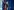 Sarah Wedl-Wilson spricht mit ernster Miene in zwei Mikrofone von TV-Sendern, sie steht vor einer blauen Wand, im Hintergrund Flaggen