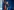 Sarah Wedl-Wilson spricht mit ernster Miene in zwei Mikrofone von TV-Sendern, sie steht vor einer blauen Wand, im Hintergrund Flaggen