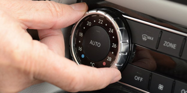 Hand dreht an Regler der Klimaanlage im Auto