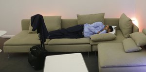 Ein Teilnehmer schläft auf einem Sofa, neben ihm sein Rollkoffer