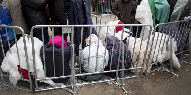 Flüchtlinge warten sitzend vor dem Lageso