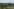 Auf einem Feld liegen Steie, es wurden große Erdlöcher ausgehoben,im Hintergrund ein Bagger. Am Horizonzt sind Windräder vor Hügelketten zu erkennen