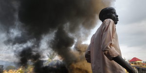 Ein Mann steht neben einer dicken Rauchschwade aus einer brennden Barrikade