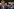 Hegseth, hinter im ein Protestschild mit der Aufschrift 