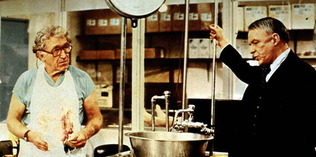 Frank Sinatra (r) steht in einer Küche, im gegenüber ein Mann mit blutverschmierter Schürze