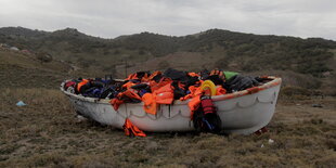 Ein Boot mit orangenen Schutzwesten steht auf einer Wiese.