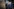 Franziska Hoppmann und Friedrich Merz gehen nebeneinander, beide tragen dunkelblaue Anzüge – im Hintergrund ein großes Foto von Konrad Adenauer