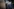 Franziska Hoppmann und Friedrich Merz gehen nebeneinander, beide tragen dunkelblaue Anzüge – im Hintergrund ein großes Foto von Konrad Adenauer