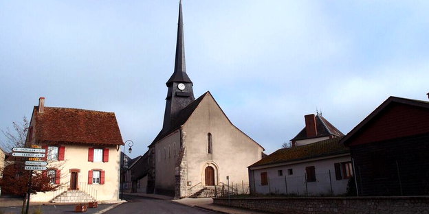 Ein Kirchturm und ein paar Häuser in einem französischen Dorf