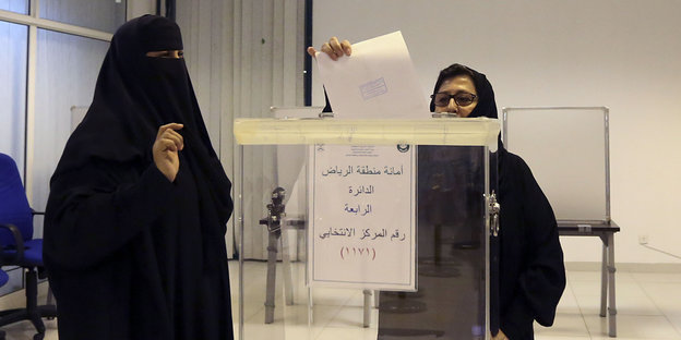 Zwei Frauen, eine davon verschleiert, bei der Stimmabgabe der Kommunalwahl in Saudi-Arabien