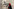 Frau mit rotem Kopftuch und schwarzer Maske vor einer Wand mit Grafitti