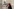 VerFrau mit rotem Kopftuch und schwarzer Maske vor einer Wand mit Grafitti