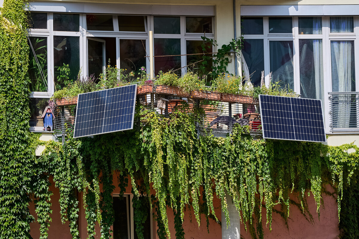 Solarpaneele hängen an einem begrünten Balkon