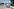 Einn bunt bemalter Wagen steht auf einer sonnenbeschienen Straße in Bolivien, hinter der sich eine Stadt bis zum Horizont erstreckt