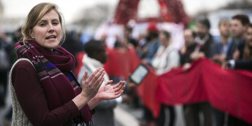 Eine Frau klatscht in die Hände, im Hintergrund stehen DemonstrantInnen