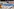 Installation zum EU-Asylsystem auf dem Stuttgarter Marienplatz im Juni 2023, in der umzingelt von Maschendrahtzaun eine EU-Flagge und Strandutensilien liegen.