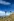 Ein mann steht neben Wegweiseren in einer Berglandschaft und blickt suchend durch ein Fernglas