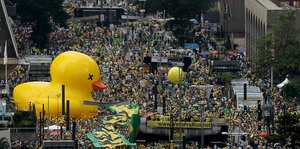 Eine riesige gelbe Ente und Demonstrierende in Sao Paulo