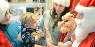 junge Eltern mit Kind, das vom Weihnachtsmann beschenkt wird