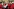 Filmszene, Männer in roten Fantasieuniformen, im Hintergrund eine Frau nehmen sich Sekt von einem Silbertablett