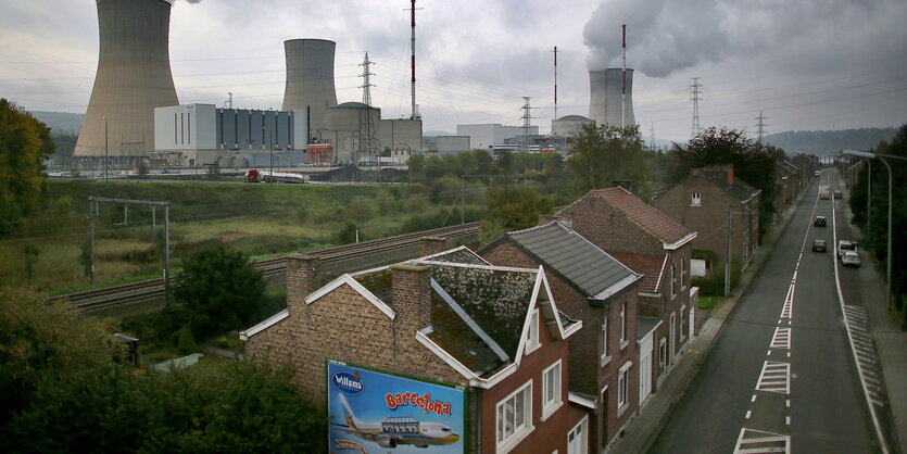 eine Straße mit Einfamilienhäusern, dahinter Bahngleise und das AKW Tihange