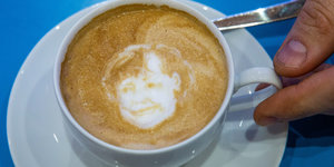 Cappuccinotasse mit Merkelbild im Milchschaum