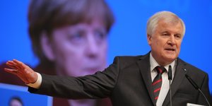 Horst Seehofer während seiner Rede, im Hintergrund das Gesicht Angela Merkels auf einer großen Leinwand.