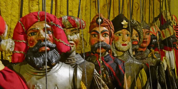sizilianische Puppen hängen nebeneinander an Schnüren