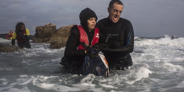 Ein Mann hilft einer Frau im Meer aus dem Wasser