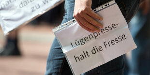 Hand hält Blatt mit der Aufschrift „Lügenpresse halt die Fresse“