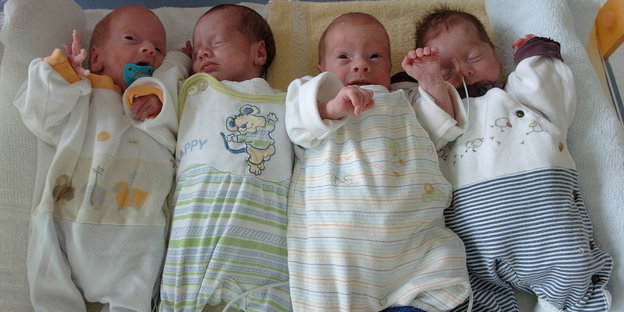 Vier Babies liegen auf einem Tuch