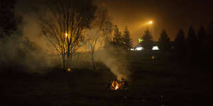 Flüchtlinge sitzen um ein Lagerfeuer